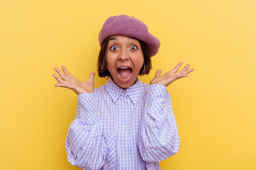 Young mixed race woman wearing a beret isolated on yellow background celebrating a victory or success, he is surprised and shocked.