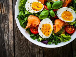 Salmon salad - smoked salmon hard boiled eggs and green vegetables on wooden table
