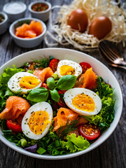 Salmon salad - smoked salmon hard boiled eggs and green vegetables on wooden table
