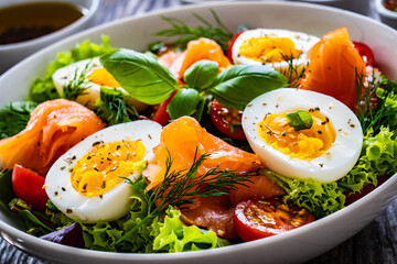 Salmon salad - smoked salmon hard boiled eggs and green vegetables on wooden table
