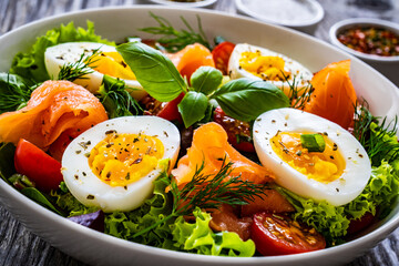 Salmon salad - smoked salmon hard boiled eggs and green vegetables on wooden table
