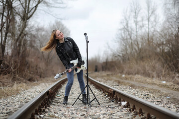  A rock musician girl in a leather jacket with a guitar