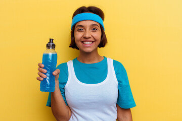 Young sport mixed race woman isolated drinking an energy drink on yellow background