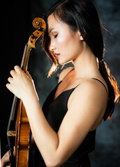 Young asian woman is holding a musical instrument a violin. Violin and violinist. Musician. Concert. © Victoria