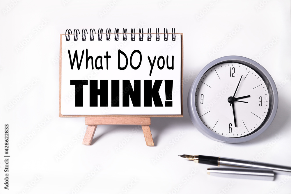 Poster what do you think? text on white notepad paper on white background. near the table clock