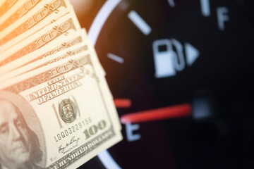 Dollar bills against oil mileage dashboard background