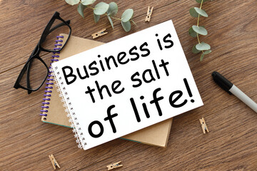 on a wooden background there are two notepads near glasses and a black felt-tip pen. Business is the salt of life!