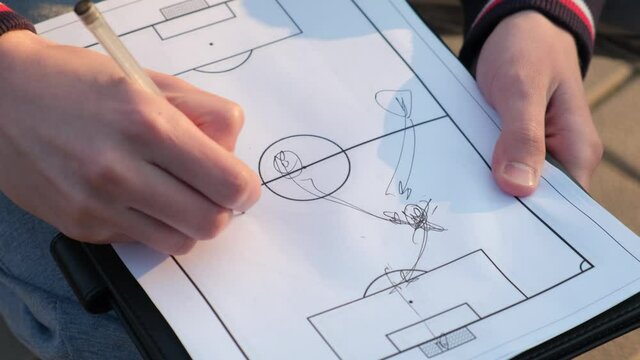 Football coach explaining the goal combination to the players on a piece of paper, close-up