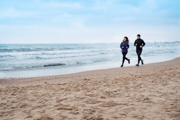 couple running along stone beach on morning