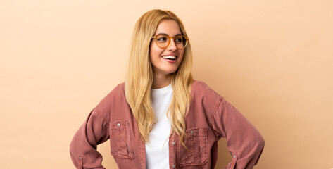 Young Uruguayan blonde woman over isolated background posing with arms at hip and smiling