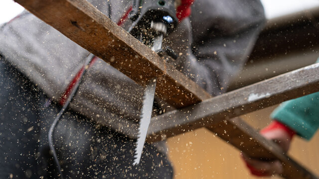 a worker saws wooden slats with a sawing machine
