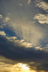 Blue sky with clouds and sunbeams at sunset