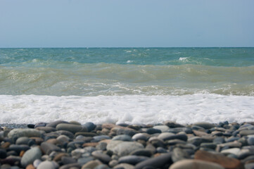 Fototapeta na wymiar The Sea Wave of the Black Sea is a pebble beach. Smooth horizon, blue sky.