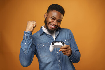 Young african american man holding joystick playing video games, yellow background © fotofabrika