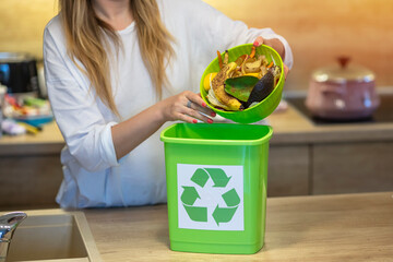 Responsible woman hands throwing away veg remains to the compost recycling container. Ecology...