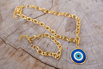 Closeup shot of a gold necklace with an eye amulet on a wooden background