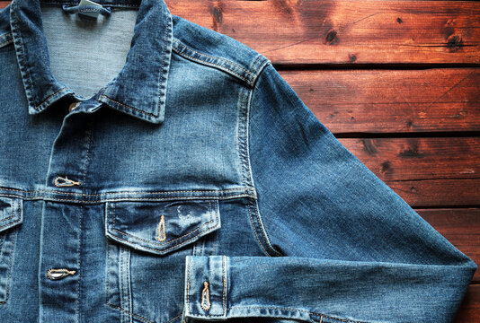Giacca di jeans blu su fondo in legno. Direttamente sopra. Concetto di abbigliamento di moda.