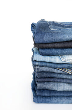 Pila di blue jeans isolati su sfondo bianco. Concetto di abbigliamento di moda.