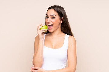 Young caucasian woman isolated on beige background eating an apple