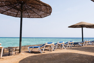 Sun loungers and thatched umbrellas along beach Blue beach chairs with Sea View