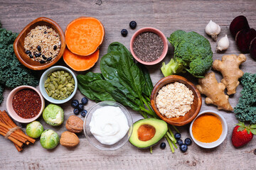 Group of healthy food ingredients. Top view table scene on a wooden background. Super food concept with green vegetables, berries, whole grains, seeds, spices and nutritious items.