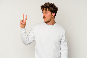 Fototapeta premium Young caucasian man isolated on white background joyful and carefree showing a peace symbol with fingers.