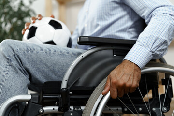 Invalid or disabled man sitting on wheelchair and holding soccer ball