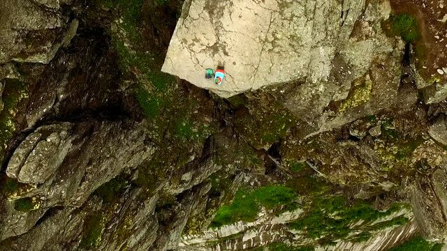 Troll's tongue. cheerful girl lies on the edge of the abyss. Aerial top view. Extreme tourism