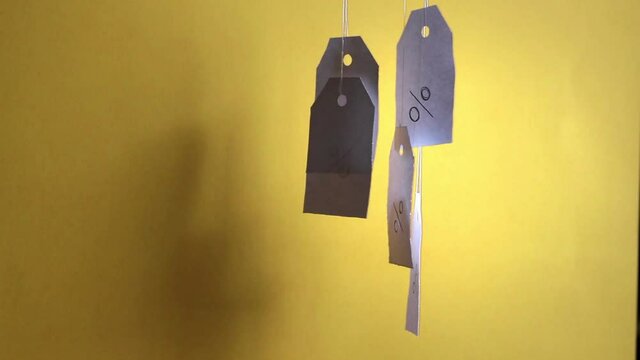 White tags with the percent sign hang, flying and swaying on strings on a yellow background with shadows. Commerce, discount, sale, trade offer. Copy space, mock up.