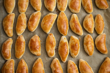 Top of view to the fresh baked meat pies on iron tray.