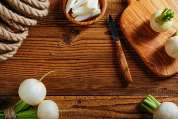 Radishes white on a wooden table with a knife and a plank for slicing made of olive wood. The concept of food. Copy the space for the text.