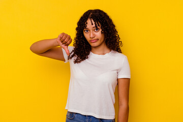 Young mixed race woman isolated on yellow background showing a dislike gesture, thumbs down....