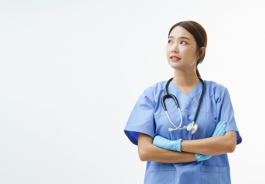 Medium Close Up Portrait Of Asian Female Doctor Or Nurse Wearing Gloves Cross Her Arm And Look Up On Her Right Direction Stand Over White Background With Copy Space. Concept Of Health Care Hero.