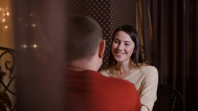 Portrait smiling woman sitting at table in cafe on romantic date with man. Happy woman laughing on evening rendezvous in romantic restaurant