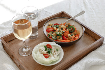 Mixed Bell-pepper Salad with Lettuce egg wrap on a brown tray in room with plants and sunshine through the window