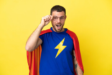 Super Hero Brazilian man isolated on yellow background with glasses and surprised