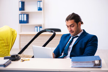 Young male employee looking after kid at workplace