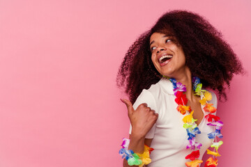 Young african american woman wearing a hawaiian stuff points with thumb finger away, laughing and carefree.