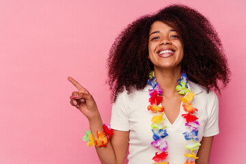 Young african american woman wearing a hawaiian stuff smiling and pointing aside, showing something...