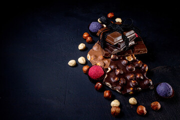 Chocolate bar, crushed pieces of dark chocolate and nuts. Praline Chocolate sweets. Copy space