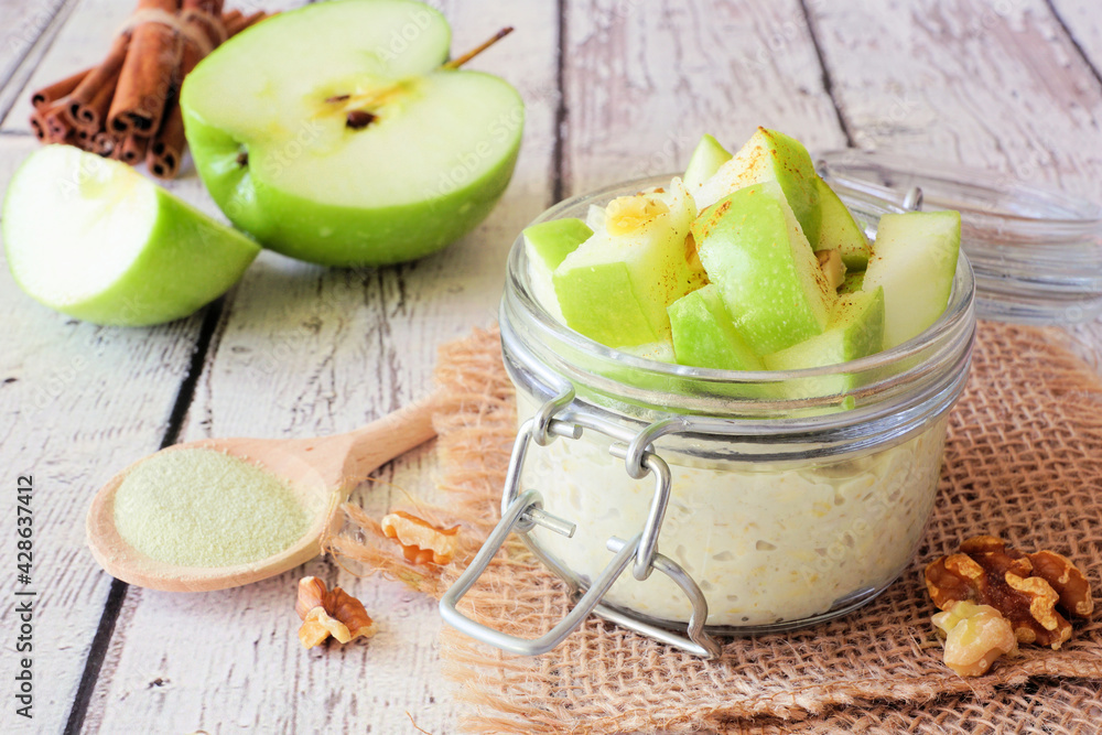 Wall mural overnight oats with matcha and green apples in a jar. table scene with a rustic white wood backgroun