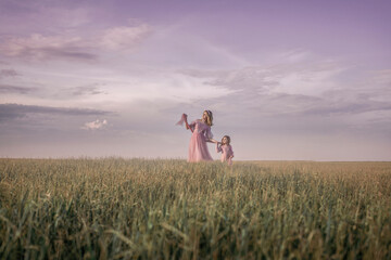 Mom and daughter are walking in a spring field in the rays of the setting sun