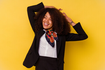Young African American air hostess isolated on yellow background stretching arms, relaxed position.