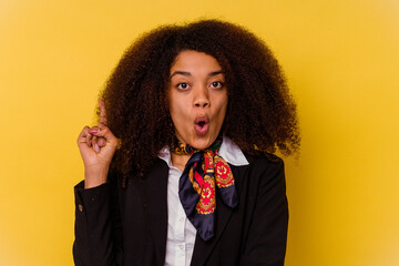 Young African American air hostess isolated on yellow background having some great idea, concept of...
