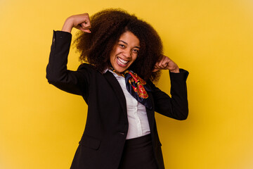 Young African American air hostess isolated on yellow background showing strength gesture with...