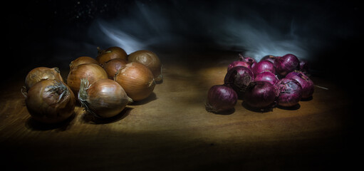 Vegetable concept. Onions in dark on wooden table. Selective focus