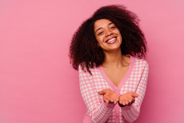 Young african american woman isolated on pink background folding lips and holding palms to send air kiss.