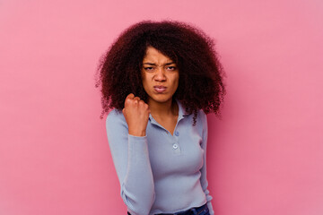 Young african american woman isolated on pink background showing fist to camera, aggressive facial expression.