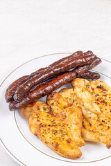 Delicious chicken breasts fried and served with fried sausages on the plate