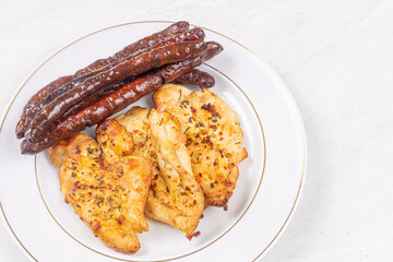 Delicious chicken breasts fried and served with fried sausages on the plate